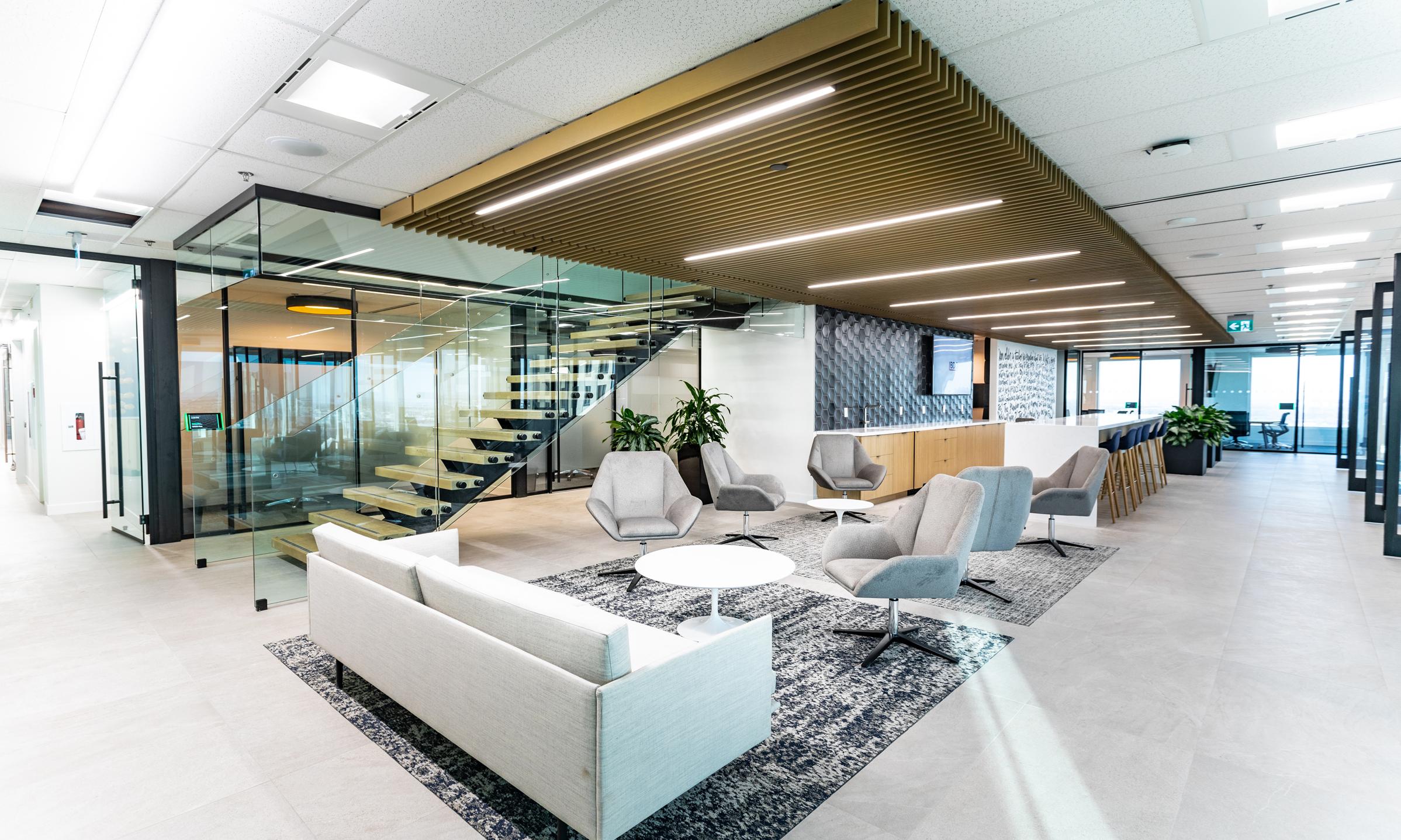 BDO Winnipeg. The new, lower-level client lounge showing the staircase to the upper floor and comfortable seating in the foreground.