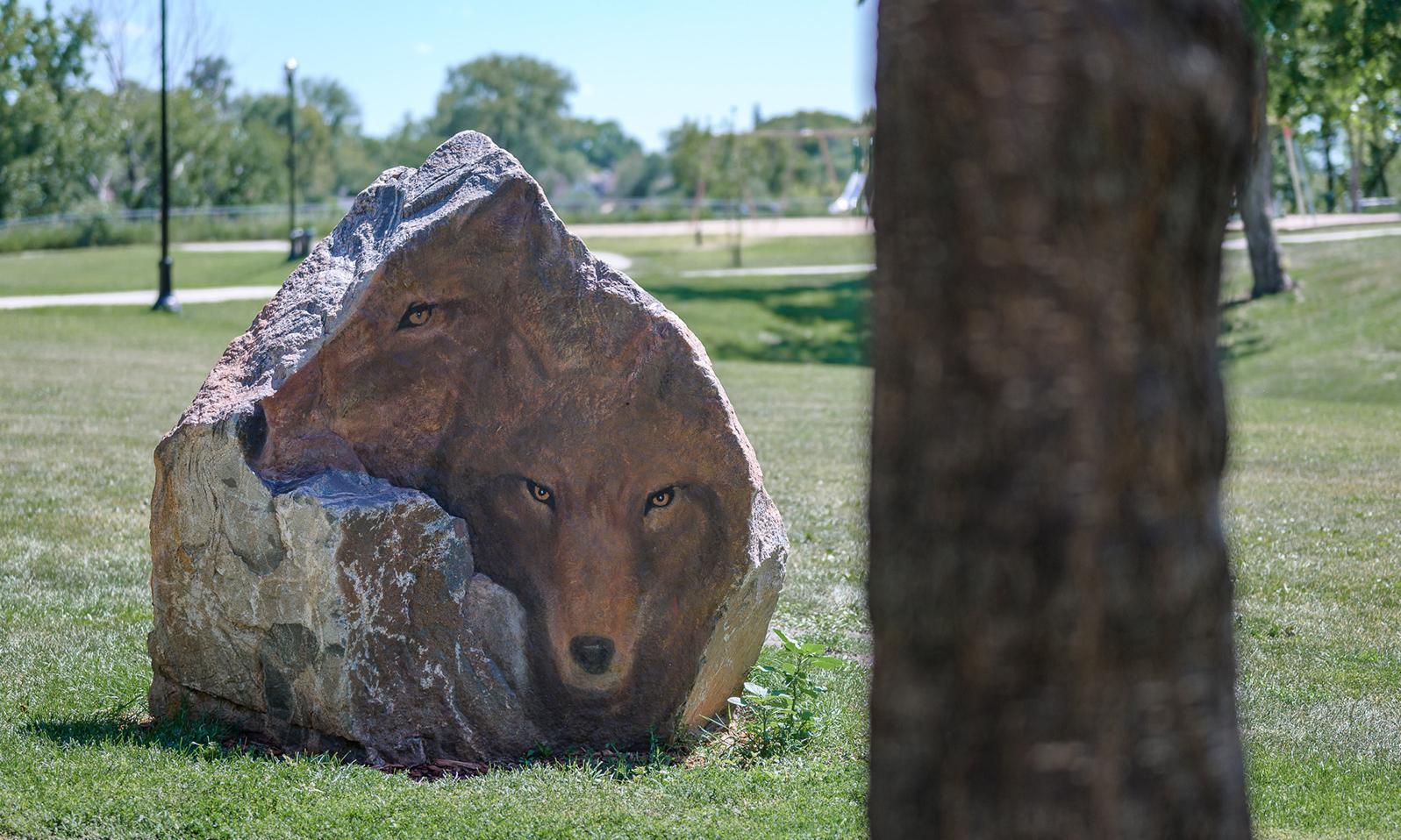 A large boulder with the faces of two wolves painted on it sits prominently in the park facing the healing forest.