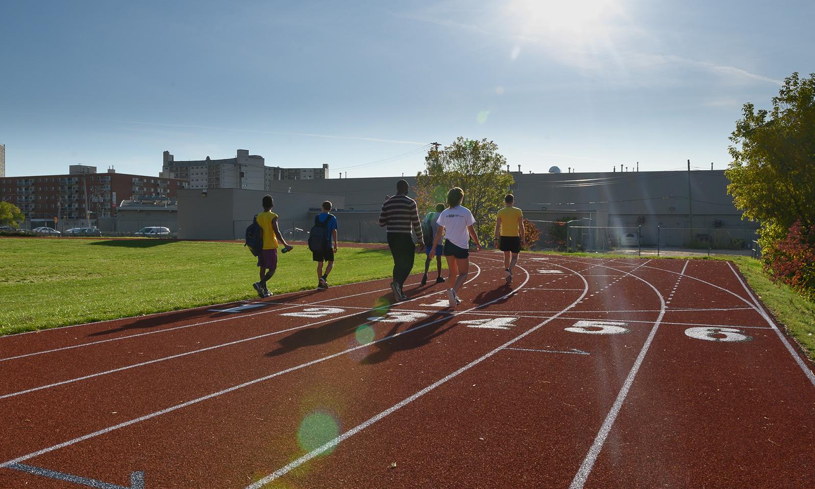 Victor Mager Running Track. Athletes walking down the inside curve of the six lane track on a bright summer day. 